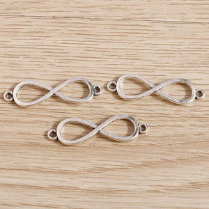 Tres colgantes de infinito en plata antigua sobre madera para creación de joyería DIY