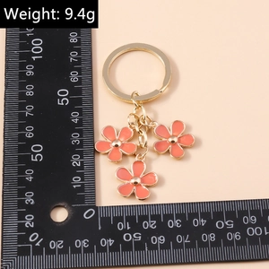 Detail view of pink enamel cherry blossom keychain with gold hardware and size scale