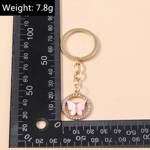 Detail of pink acrylic butterfly keychain with rhinestones showing 3cm size on ruler