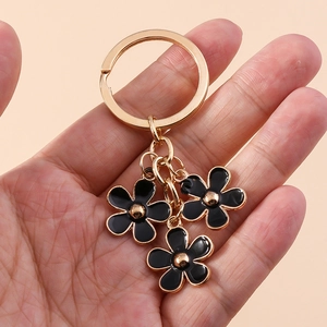 Close-up of three black enamel cherry blossom charms on a gold-tone keychain hook