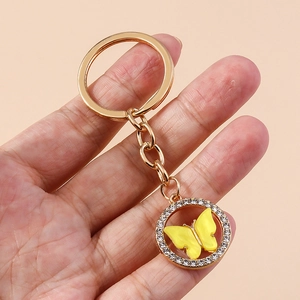 Detail of a golden butterfly keychain with shimmering rhinestones and yellow acrylic charm