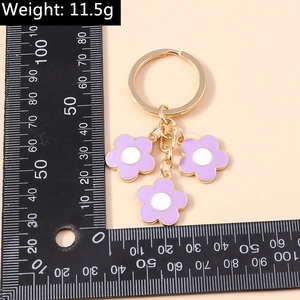 Detailed view of sweet purple floral keychain charm with gold metal ring and measurement scale