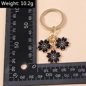 Détail du porte-clés fleur de cerisier en émail noir avec règle de mesure et métal doré