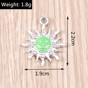 Macro shot of silver sun flower pendant with green smile face and white rhinestones