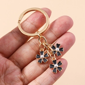 Porte-clés minimaliste doré avec trois fleurs noires et des perles élégantes