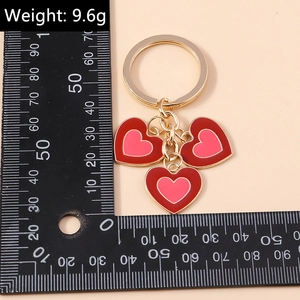 Détail du porte-clés double cœur en émail rouge et rose avec bordure dorée élégante