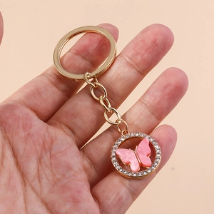 Detail of a gold butterfly keychain with sparkling rhinestones held in a hand