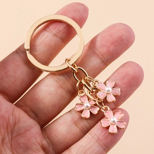 Porte-clés fleuri avec pétales en émail rose et perles sur un anneau doré poli en main