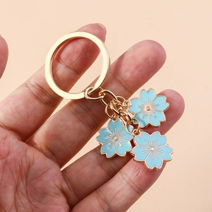 Détails de breloques cerisier en émail bleu clair sur un porte-clés en métal doré poli