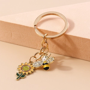Porte-clés doré avec tournesol et abeille orné de strass brillants et d'une perle