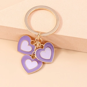 Détail d'un porte-clés doré avec des breloques cœur violettes à double couche