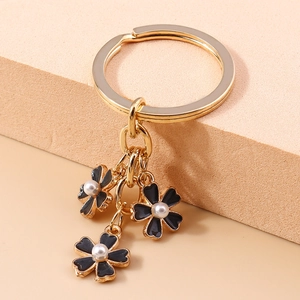 Détail du porte-clés fleur dorée avec pétales en émail noir et perles nacrées