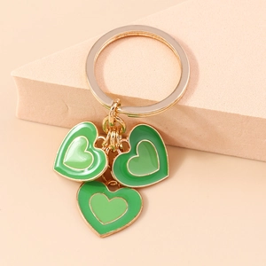Détail macro de trois pendentifs cœur en émail vert avec un anneau de clé en métal doré