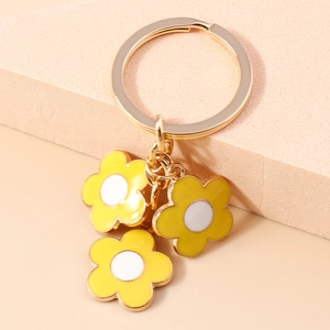 Detailed close-up of daisy charms with yellow enamel petals and golden metal key ring