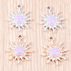 Detailed macro view of gold and silver sun flower pendants with purple enamel smiley faces