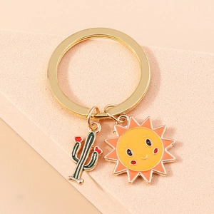 Gros plan d'un porte-clés doré en émail avec cactus et breloque soleil souriant