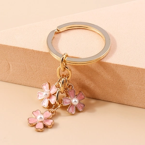 Détail des breloques fleurs de cerisier roses avec perles sur un anneau doré de porte-clés