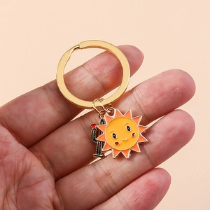 Détail de breloques tournesol et cactus sur porte-clés doré tenu à la main