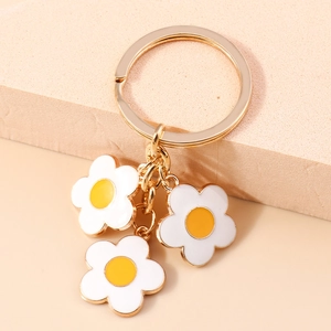 Detail shot of three white daisy flower charms on a golden keychain over pink stone