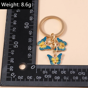 Détail d'un porte-clés papillon dégradé bleu et jaune avec un anneau doré élégant