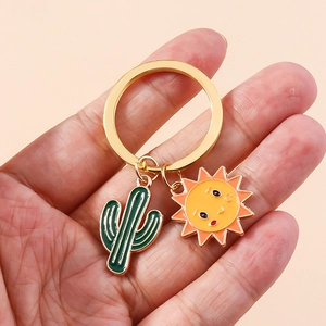 Détail de porte-clés tournesol cactus avec anneau doré tenu à la main sur rose