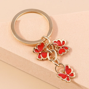Detailed macro view of a gold-plated butterfly keychain with vibrant red enamel charms