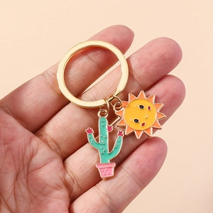 Gros plan de pendentifs tournesol et cactus dorés sur un porte-clés floral mignon