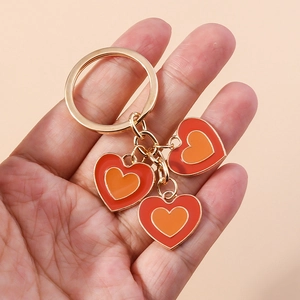 Détail du porte-clés doré avec pendentifs cœurs en émail rouge et orange superposés