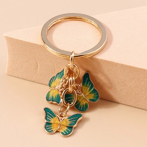 Vue macro de trois pendentifs papillons en émail dégradé sur un porte-clés doré