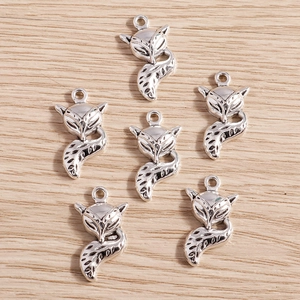 Set of 6 vintage silver alloy fox charms with detailed tail engravings on wood background