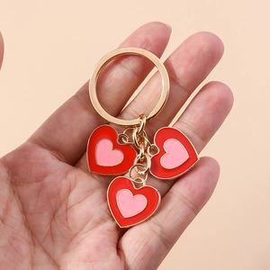 Gros plan d'un porte-clés doré avec trois breloques en forme de cœur émaillé rouge et rose