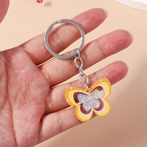 Porte-clés papillon arc-en-ciel avec paillettes et anneau métallique tenu en main