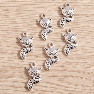 Detailed macro view of six vintage silver fox pendants on a natural wooden background
