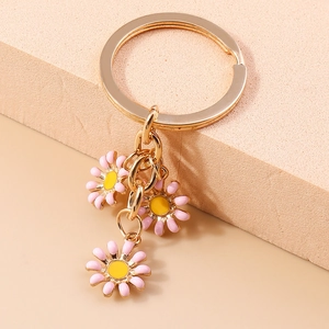 Portachiavi con margherita rosa e anelli dorati su pietra beige, accessorio borsa