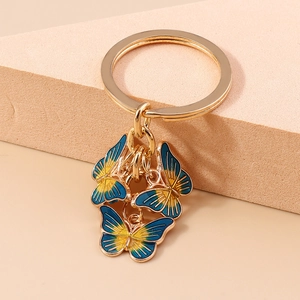 Macro de trois pendentifs papillon dégradé bleu et jaune sur un anneau porte-clés doré