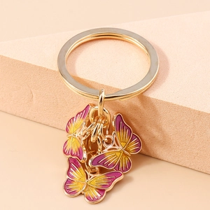 Détail du porte-clés doré orné de trois papillons en émail avec dégradé de violet et de jaune