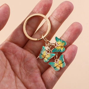 Porte-clés papillon doré avec pendentifs en émail dégradé jaune-vert en main