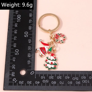 Dettaglio portachiavi natalizio con Babbo Natale e albero, peso 9,6g su uno sfondo rosa