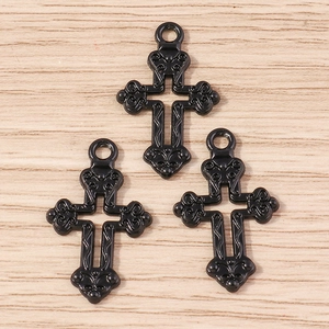 Détail de trois pendentifs croix gothiques en alliage noir sur un fond en bois clair