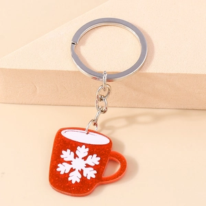 Close-up of red glitter resin mug keychain with white snowflake pattern and silver ring