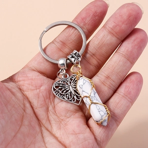 Detail of a white marble hex pillar pendant with heart butterfly charm on keychain