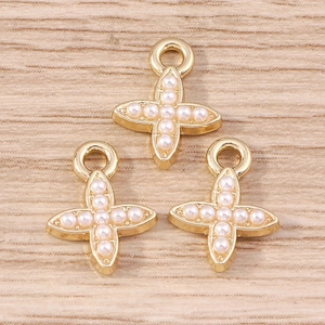Golden cross pendants with white pearls for DIY jewelry making on wooden background