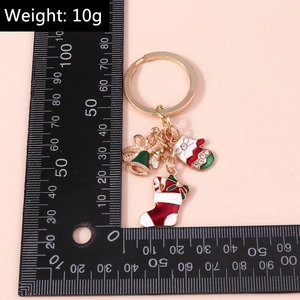 Dettaglio dei ciondoli natalizi in smalto da 10g con campanello e guanto su portachiavi