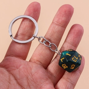 Green and gold D20 polyhedral dice keychain with silver metal ring and chain held in hand