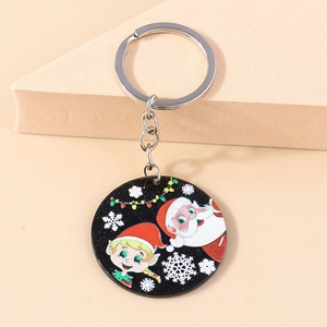 Detail of Christmas keychain with Santa Claus and elf motif on black acrylic disc