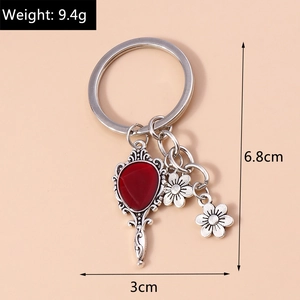 Detail of vintage silver mirror keychain with red gem and tiny flower charms