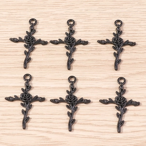 Détails de six pendentifs croix avec roses noires sur un fond en bois clair