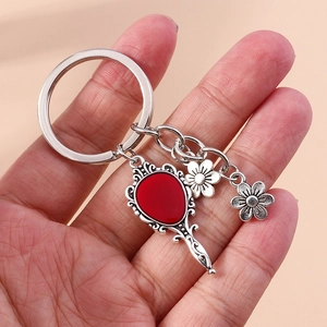 Detail of vintage silver alloy keychain featuring a red drop hand mirror and metal flowers