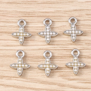 Macro detail of silver cross jewelry charms with white pearls and hanging loops