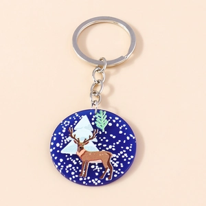 Detailed view of an acrylic elk keychain with snowflakes and forest illustration on dark blue
